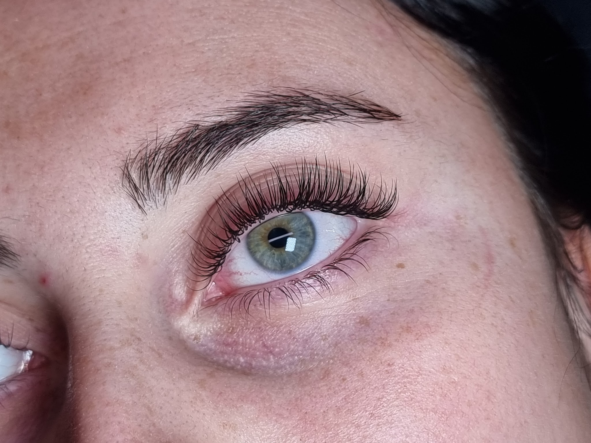 Soft, fluffy lash extensions on a green eye, seen from the side