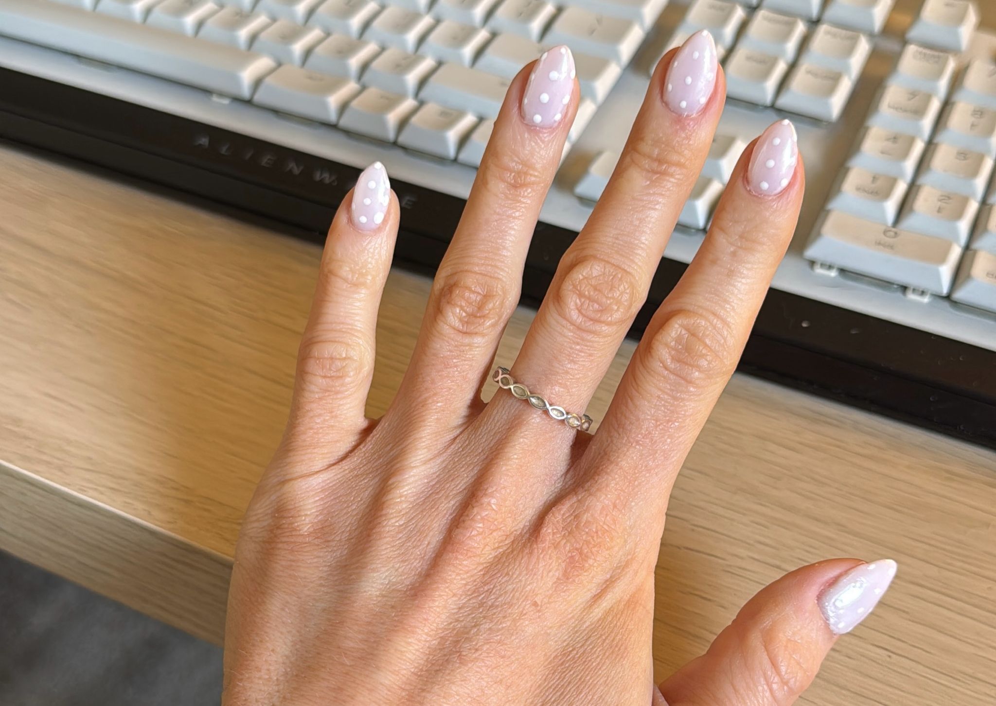 Almond nails in pale pink gel polish with tiny white dots