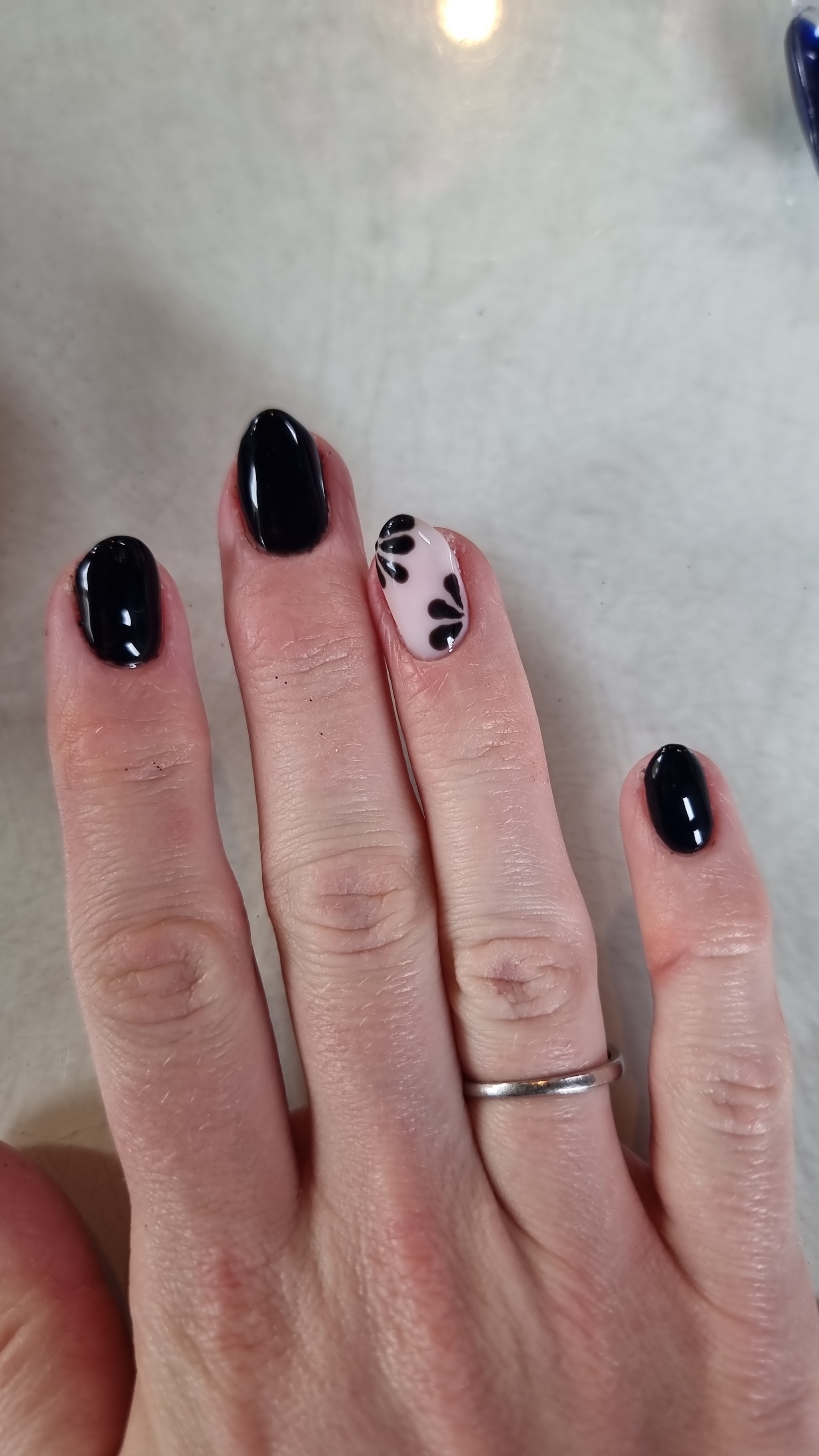 Short black gel nails with one floral accent nail